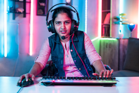 Smiling woman playing video game by talking on headphones while looking at camera at neon background - concept of tournament, entertainment and gaming addiction.の写真素材