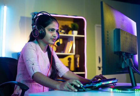 gamer seriously playing live video game on computer with headphones at home - concept of live...