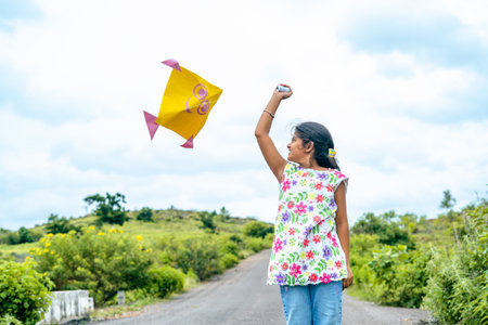 Excited happy girl kid running by flying kite during holidays - concept of holidays, playful vacation and carefree.の写真素材