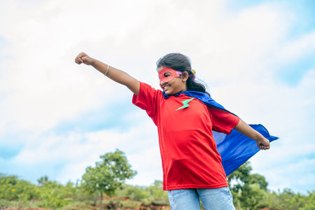 Strong Teenager girl kid in flying position looking around while standing on top of hill - concept of imagination, fantasy and powerful.の写真素材