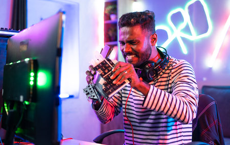 Angry frustrated gamer breaking keyboard due to loss playing video game on computer at home - concept of frustration, depression and tournamentの写真素材