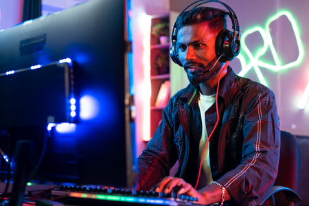 Excitd pro gamer playing online video game on computer by talking on headphone at home - concept of...