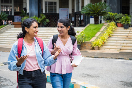 Happy smiling college students talking each other after classes at college campus - concept of taking break, friendship and education.の写真素材