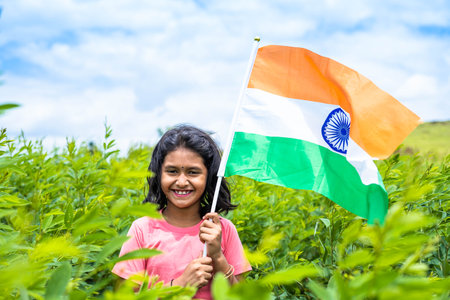 Happy smiling teenager girl holding indian flag at farmland - concept of freedom, patriotism and educationの写真素材