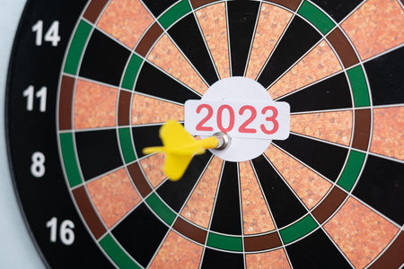 focus on tip, Close handheld shot of hands throwing dirt tip on 2023 dirt board - concept of target new year 2023, aiming for new beginningsの写真素材