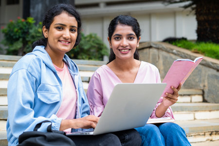 focus on girl with book, Happy College students looking at camera while busy working on laptop on university campus - concept of education, teamwork and friendshipの写真素材