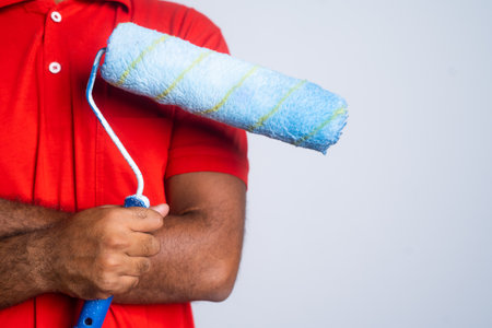 Close up shot of confident painter standing by holding paint roller brush with copy space - concept...