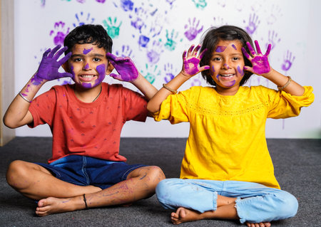Cheerful kids with messy colorful hands grimacing to camera at home - concept of mischievous, innocent and humor.の写真素材