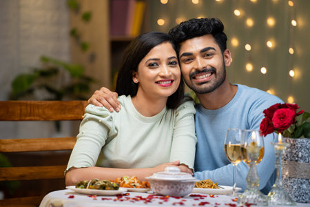 Portrait shot of happy smiling couple looking at camera during candle light dinner at home - concept of celebrating valentines day, affection and datingの写真素材