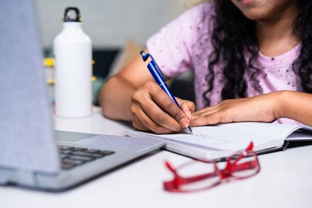 close up shot of Girl student making notes from online class using laptop at home - concept of...