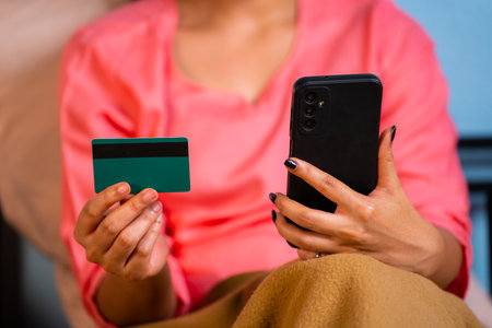 Close up shot of girl hands making online payment using credit card on mobile phone during sleeping on bed - concept of e commerce, midnight sales and discounts.の写真素材