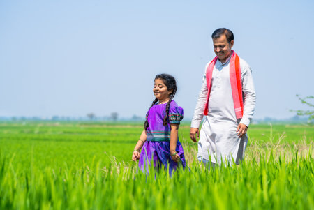 Happy indian playful kid with villager farming father at farmland - concept of freedom, rural India and caring fatherの写真素材