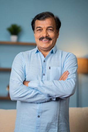 Vertical shot of Indian elderly senior man standing confidently by looking at camera with arms crossed - concept of proud, dignity and successfulの写真素材