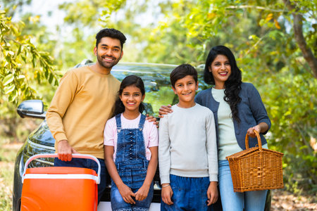 Happy smiling family with sibling kids standing in front of car for picnic by looking camera during holiday travel - concept of joyful lifestyle, family time and freedomの写真素材