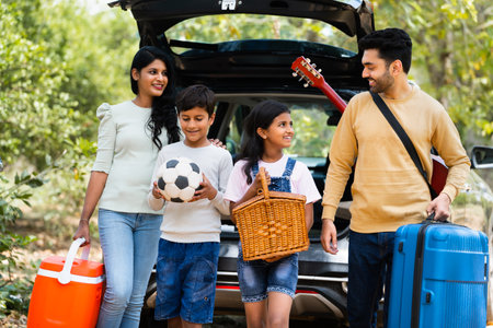 Happy indian fmaily with kids with picnic basket and travel lagguage at destination - concept safe car travel, transportation and vacation or holidays.の写真素材