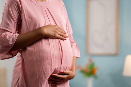 Close up shot of Pregnant woman standing by touching or feeling tummy at home - concept of expecting...
