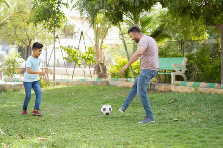 Focus on father, Happy indian father with little son playing football game at park - concept of weekend holidays, Family recreation and active bonding.の写真素材