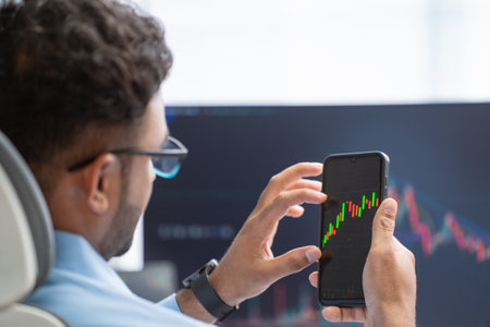 Shoulder shot of indian stock Market broker or trader checking charts on digital tablet at office -...
