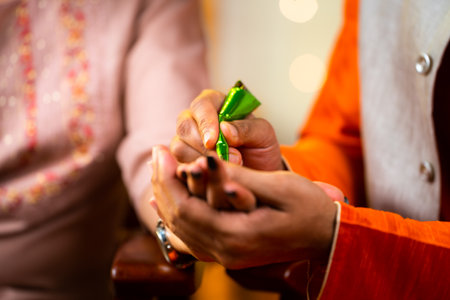 Close up shot of indian husband hands applying henna or mehndi on wifes hand durnig festival celebration at home - concept of caring relationship, preparation and traditional cultureの写真素材