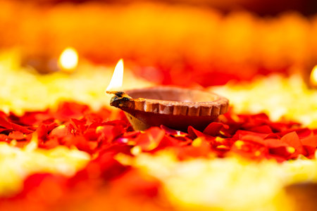 Close up shot of diya or oil lamp placed on flowers during diwali festival celebration - concept of...