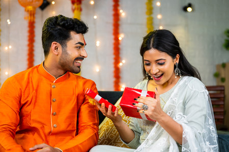 surpised indian young sister by receiving gift from brother during raksha bandhan festival celebration at home - concept of tradition culture, Sibling Bonding and Rakhi Giftingの写真素材