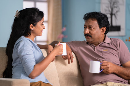 Happy indian daughter with father spending time talking while having tea together at home - concept of leisure time,Joyful Conversation and Companionshipの写真素材