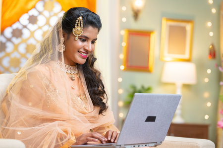 happy smiling Indian muslim womam using or working on laptop during ramadan festival at home - concept of woman empowerment, social media sharing and surfing web.の写真素材