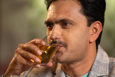 Close up shot of middle aged Indian man drinking wine at weekend night party at restaurant - concept of luxury lifestyles, refreshment and relaxationの写真素材