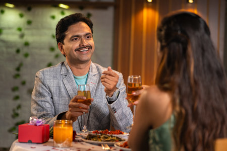 Shoulder shot, curious husband talking with wife during candle light dinner at anniversary or birthday celebration - concept of romantic date night, affection and companionの写真素材