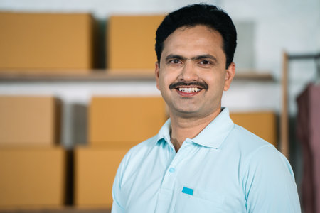 Happy indian confident small businessman at merchandise wear house looking at camera - concept of entrepreneur, successful startup and manager.の写真素材