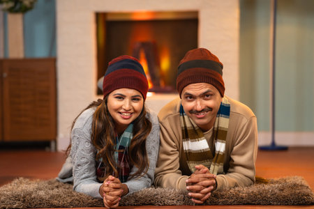 Happy portrait smiling Indian loving couples in winter wear looking at camera while laying on floor - concept of companionship, family bonding and romantic relationship.の写真素材