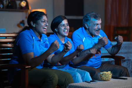 Cheerful family shouting as India india while watching live cricket match on tv or television for...