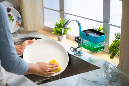 Close up shot of woman hands washing dishes or utensils at kitchen using liquid soap - concept of household domestic work and routine houseworkの写真素材
