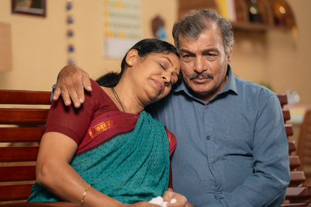 Indian senior husband consoling his worried crying wife at home - concept of emotional family support, companionship and kindnessの写真素材