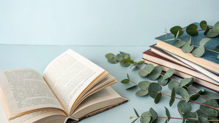 Open book, books and eucalyptus branches on blue backgroundの写真素材