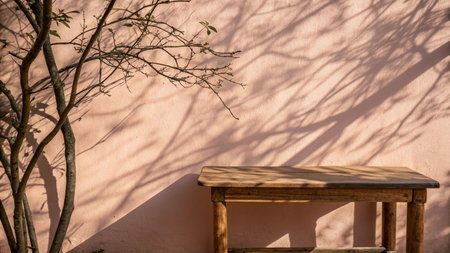 Wooden table and shadow of tree on pink wall. Abstract background.