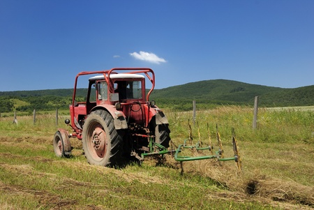 A red tractor pulls a hay rakeの写真素材