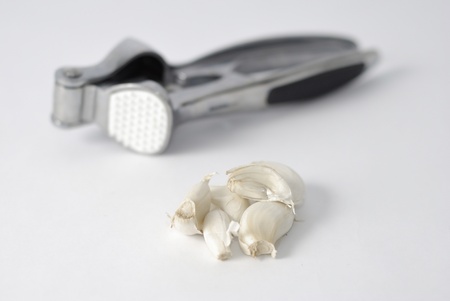 Garlic press and slices of garlic, isolated on a grey background の写真素材
