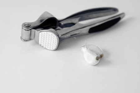 Garlic press and slices of garlic, isolated on a grey background の写真素材