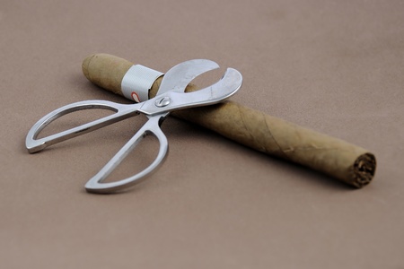 Cigar and scissors over a brown backgroundの写真素材