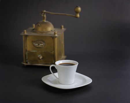 A cup of coffee with a coffee grinder on black backgroundの写真素材