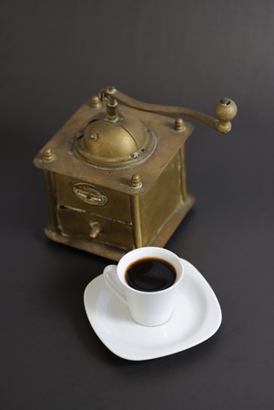 A cup of coffee with a coffee grinder on black backgroundの写真素材