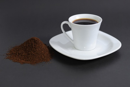Ground coffee and a cup over a black backgroundの写真素材