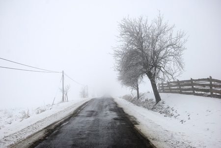 Snowy road in the mountains with hoary fence and treesの写真素材