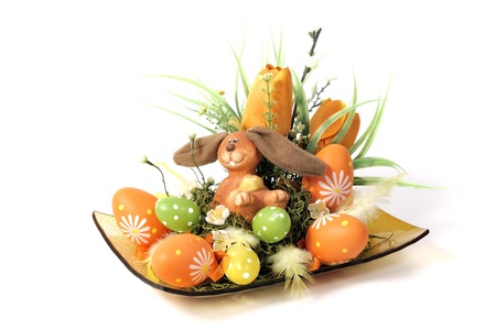 Easter decoration - bunny in a wicker basket with flowers and eggs in green, orange and yellowの写真素材