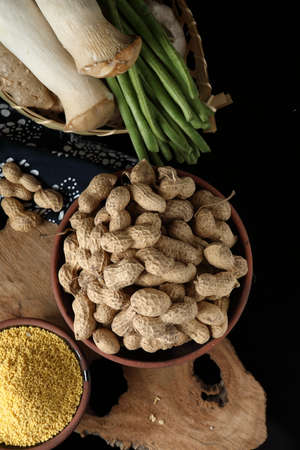 Peanut in a bowl and raw peanuts in a bowl on a black backgroundの写真素材
