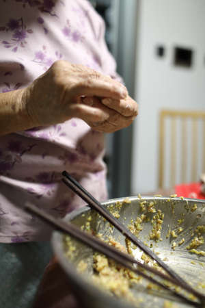 Elderly woman cooking food in the kitchen. Selective focus.の写真素材