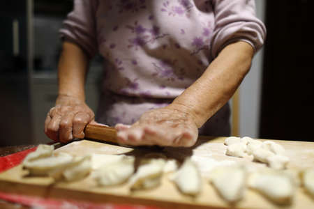 Close-up of the hands of an elderly woman kneading the dough with a rolling pinの写真素材