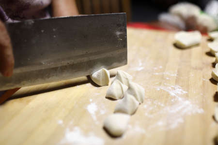 Close-up of a woman's hands cutting the dough with a knife.
