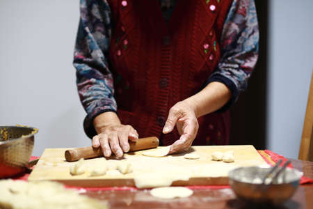 Close-up of a woman's hands rolling out the dough on a wooden board